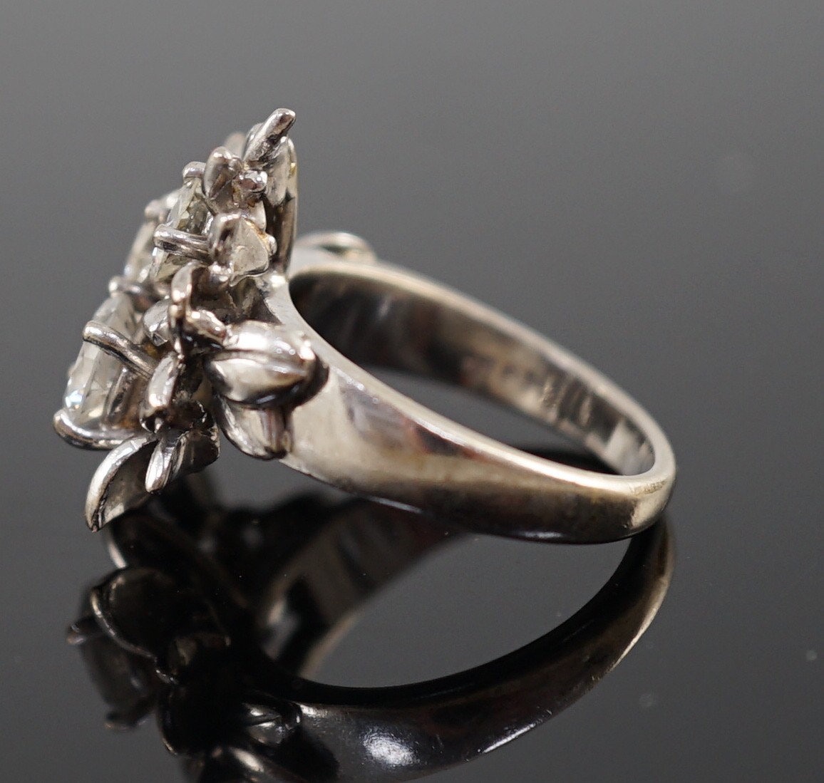 An 18ct white gold and three stone diamond set flowerhead ring